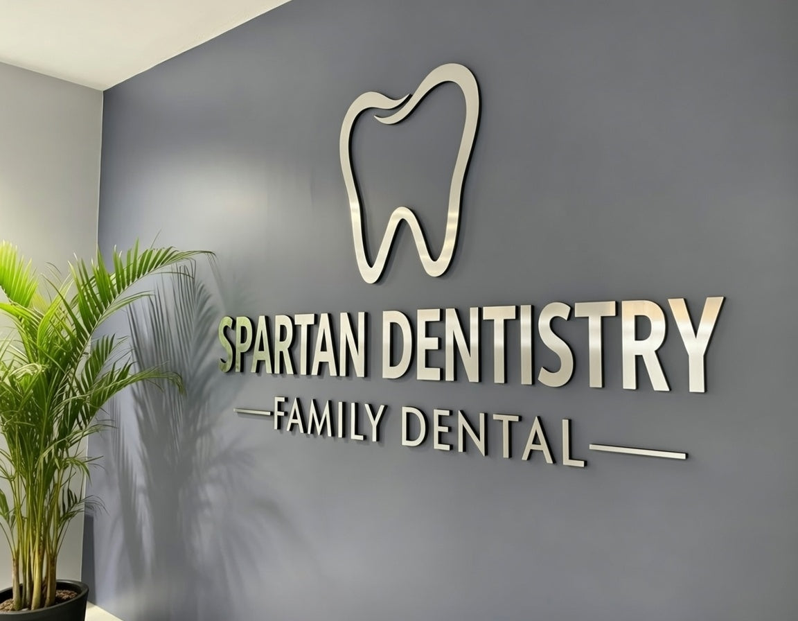 Spartan Dentistry Family Dental logo on a gray wall with a plant in the foreground. Laser Cut from Aluminium Sheet