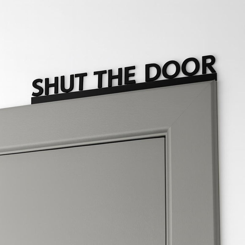 Funny shut the door sign mounted above internal door frame