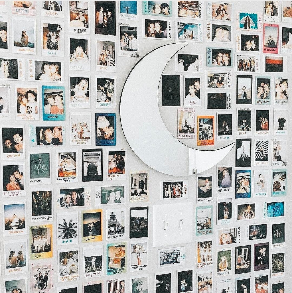 Wall with a grid of small photo frames arranged on a wall around a acrylic gold moon 